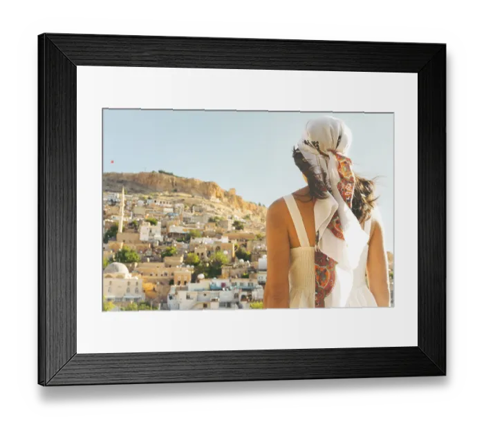 Framed Print : Traveler woman in white dress looking over panoramic view of historic city of Mardin Turkey with mosque minarets