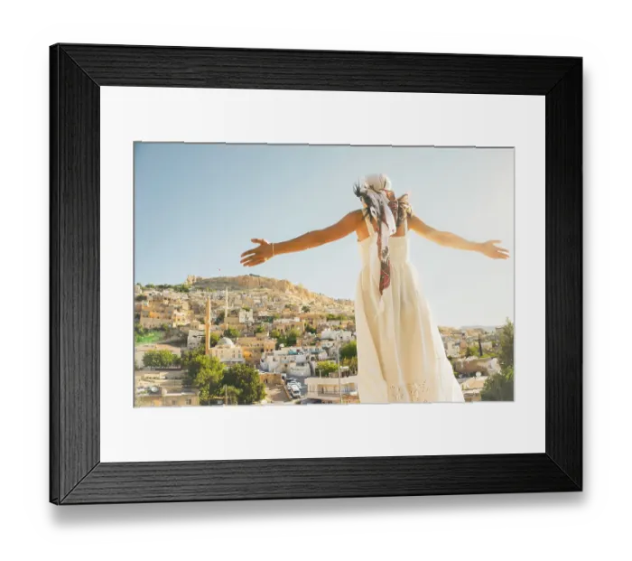 Framed Print : Traveler woman in white dress arms outstretched looking over panoramic view of historic city of Mardin Turkey with