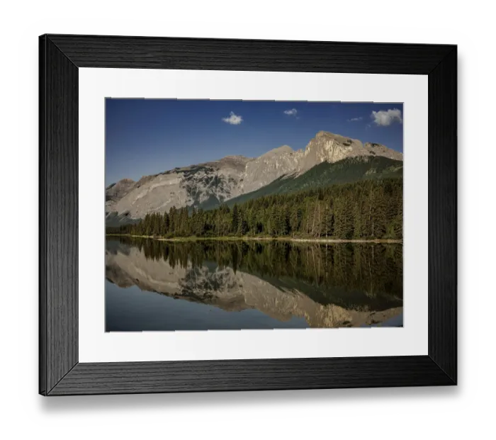 Framed Print : Quiet, reflective waters mirror the surrounding Canadian Rocky Mountains and forest near Canmore