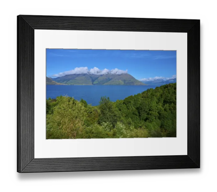 Framed Print : Lush green landscape with mountains in the background and a blue lake Framed Print : Lush green landscape with mountains in the background and a blue lake