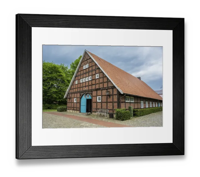 Framed Print : Traditional half-timbered house with red tiled roof and green surroundings under a cloudy sky