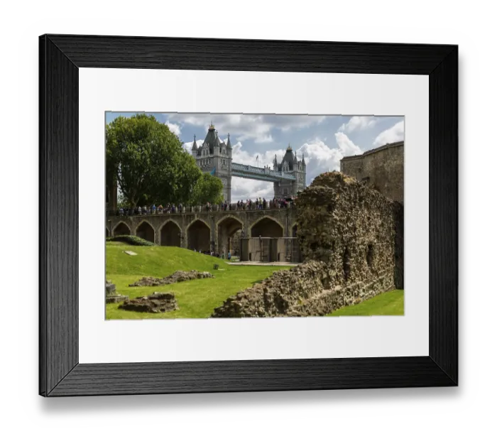 Framed Print : Arched stone structure with tourists under a partly cloudy sky at The Tower of London with Tower Bridge