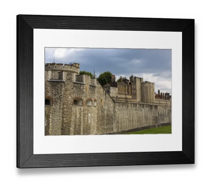 Framed Print : Historic stone wall and towers under a cloudy sky at The Tower of London
