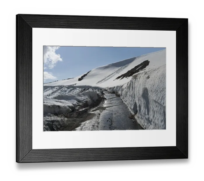 Framed Print : Snow-covered road between snow-covered mountains under a clear blue sky Framed Print : Snow-covered road between snow-covered mountains under a clear blue sky