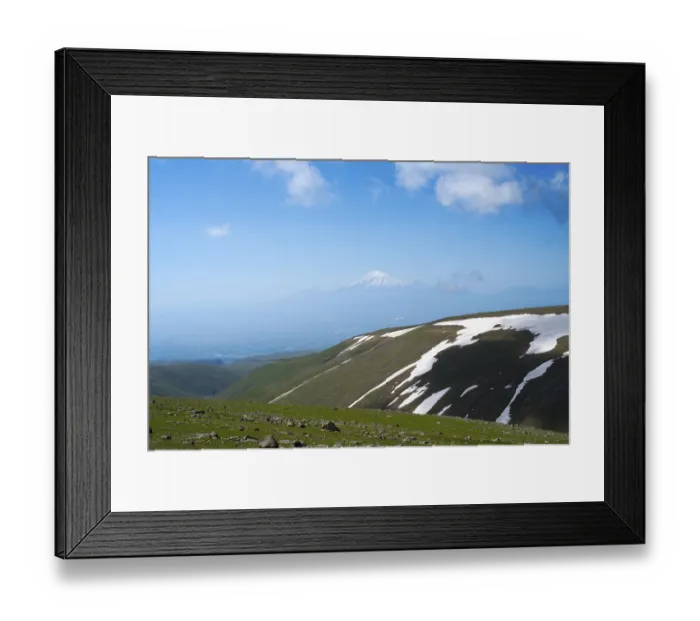 Framed Print : Green mountain landscape with snowfields and cloudy sky in the distance Framed Print : Green mountain landscape with snowfields and cloudy sky in the distance