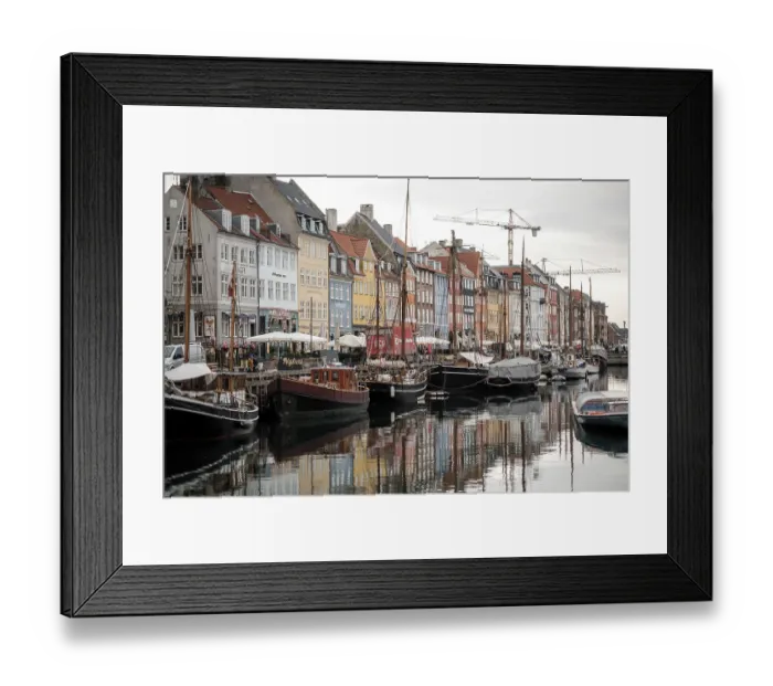 Framed Print : Boats docked along a waterfront with rows of colorful buildings reflecting in the water in Nyhavn