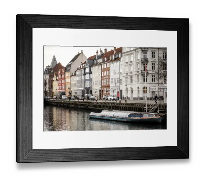 Framed Print : A small boat moored along a canal flanked by rows of colorful buildings in Nyhavn
