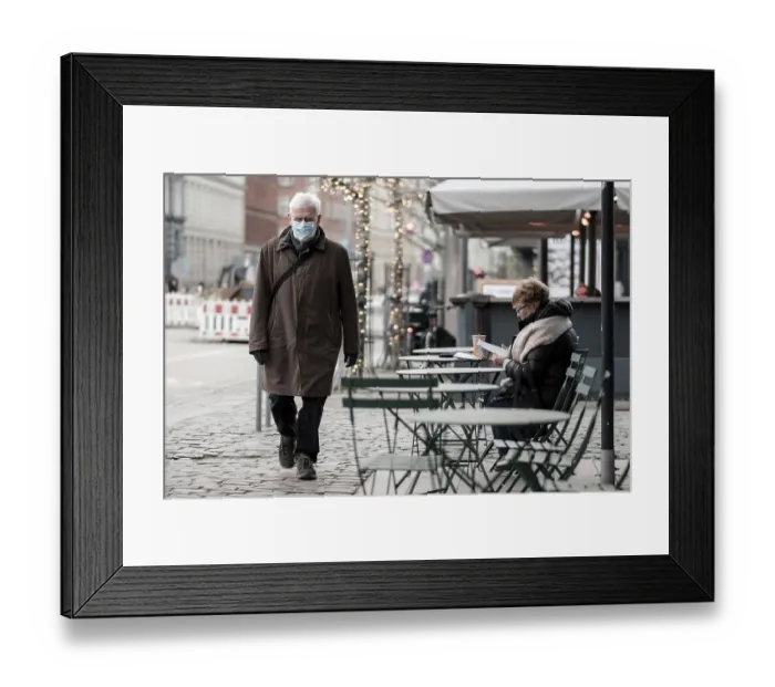Framed Print : An elderly man walks past a woman reading at an outdoor cafe Framed Print : An elderly man walks past a woman reading at an outdoor cafe
