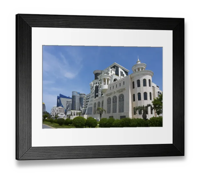 Framed Print : A modern building with an elegant design surrounded by palm trees and green spaces under a blue sky Framed Print : A modern building with an elegant design surrounded by palm trees and green spaces under a blue sky