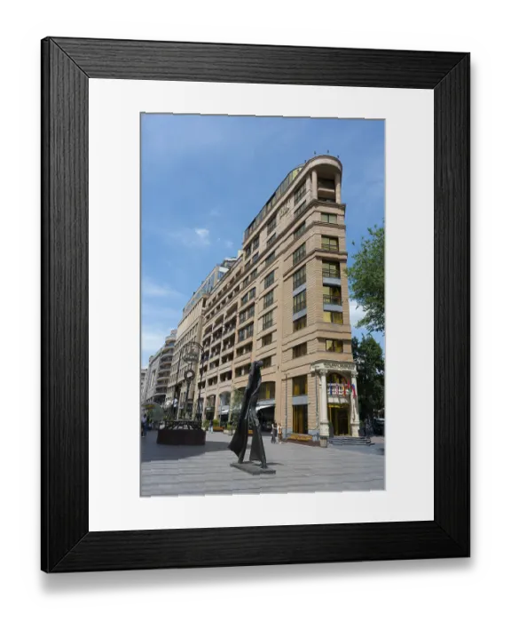 Framed Print : Tall building in an urban environment with a unique statue in front of it