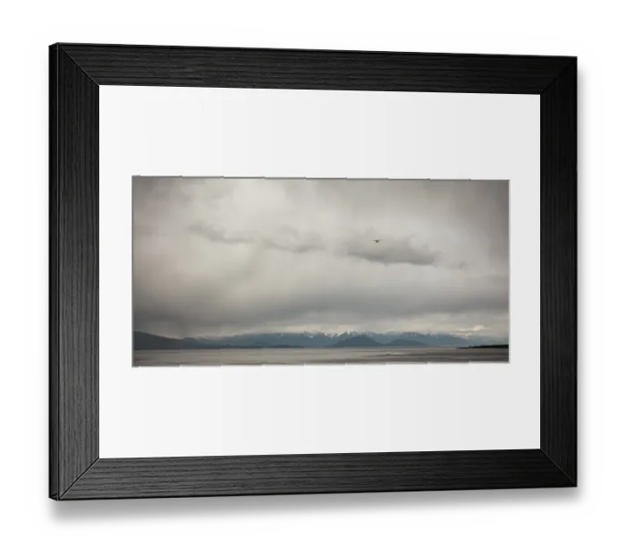 Framed Print : A small airplane flies over a wide area with distant mountains as seen from deck of passenger ferry crossing the Salish