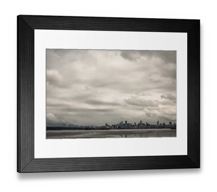 Framed Print : City skyline with towering buildings under a cloud-filled sky