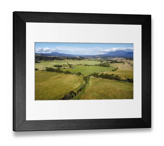 Framed Print : Wide green fields under a cloudy blue sky with mountains in the background Framed Print : Wide green fields under a cloudy blue sky with mountains in the background