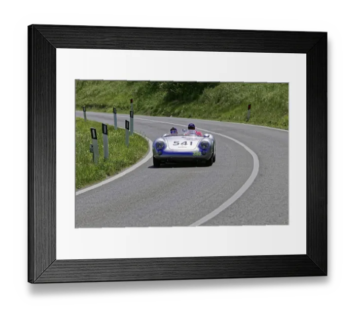 Framed Print : A silver racing car with two people drives swiftly along a winding road