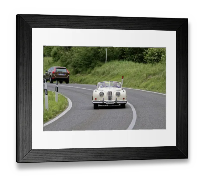 Framed Print : A classic convertible drives along a winding country road surrounded by green countryside
