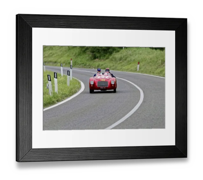 Framed Print : A red convertible sports car with two drivers on a winding country road