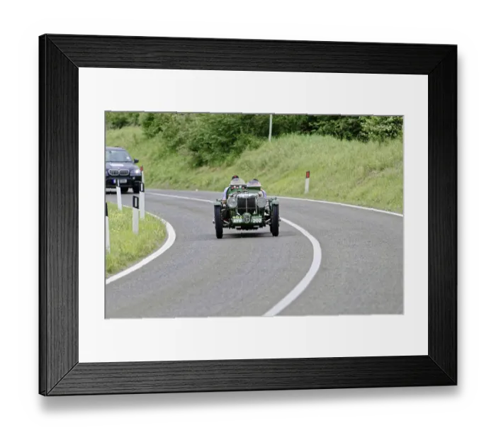 Framed Print : Green vintage car drives on winding country road