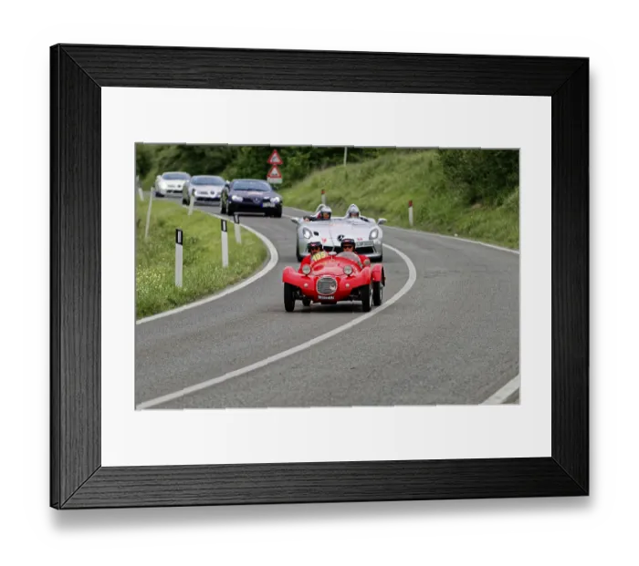 Framed Print : Two people with helmets in a red classic car on a country road