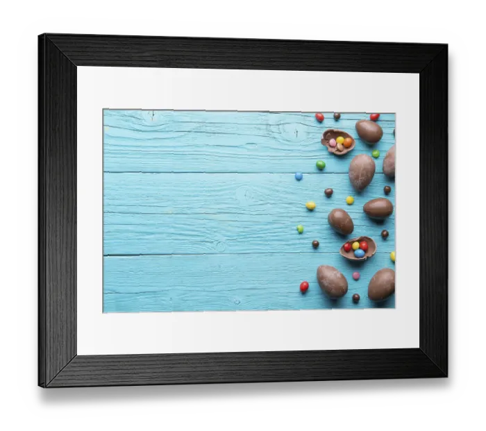 Framed Print : Halves of chocolate eggs, sweets on blue wooden table Framed Print : Halves of chocolate eggs, sweets on blue wooden table