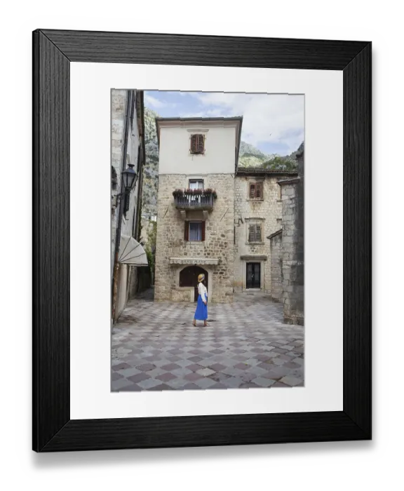 Framed Print : A girl in a blue dress and a straw hat walks through the old town of Kotor
