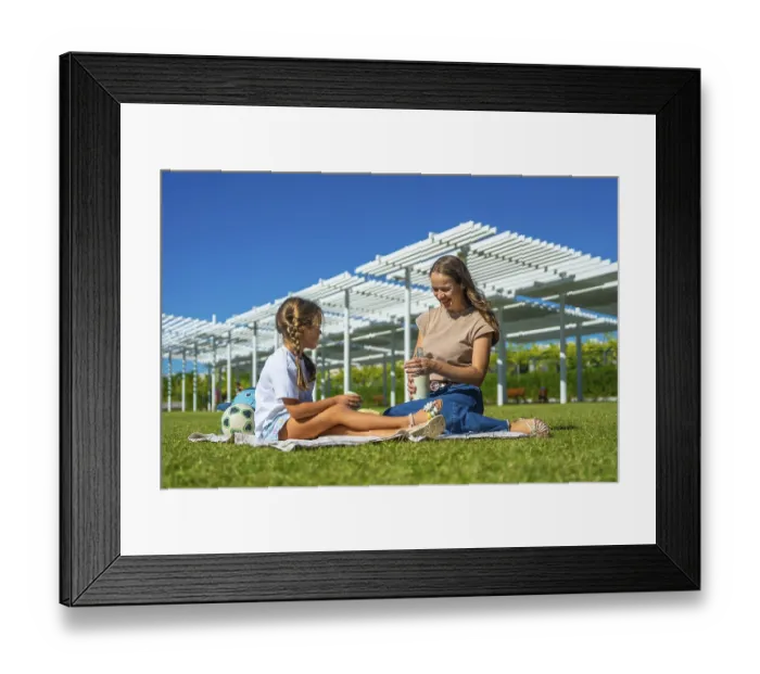 Framed Print : Mother and daughter sitting on a picnic blanket in a sunny urban park