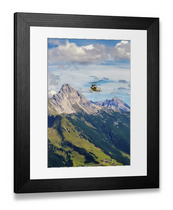 Framed Print : A helicopter flies over a mountainous region under a cloudy sky Framed Print : A helicopter flies over a mountainous region under a cloudy sky