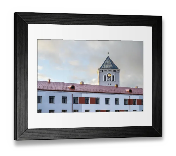 Framed Print : A white tower with a clock and a fragment of a modern building on the background of the sunset sky Framed Print : A white tower with a clock and a fragment of a modern building on the background of the sunset sky
