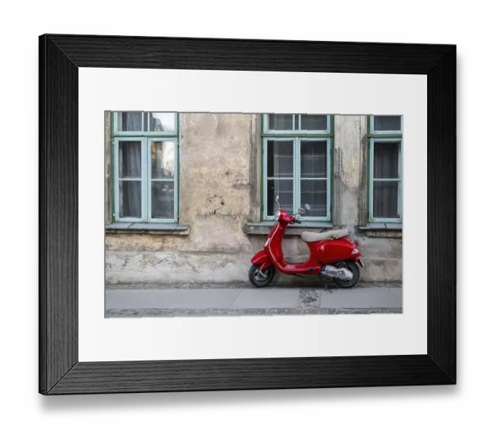 Framed Print : A red vintage scooter on a pedestrian sidewalk in front of an old stone house