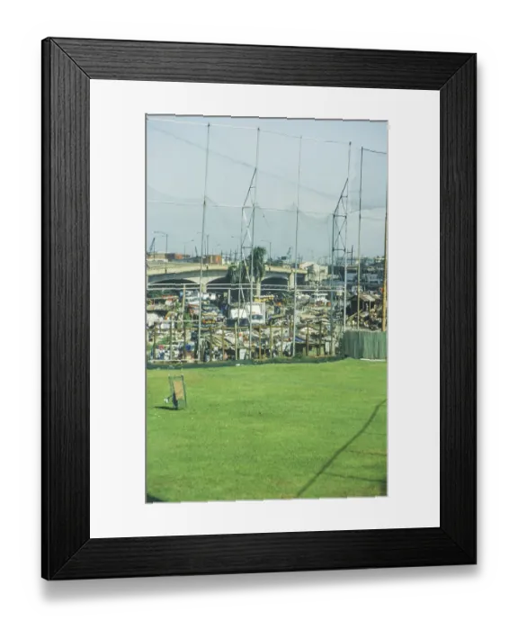 Framed Print : Green lawn of a sports field, slums behind it Framed Print : Green lawn of a sports field, slums behind it