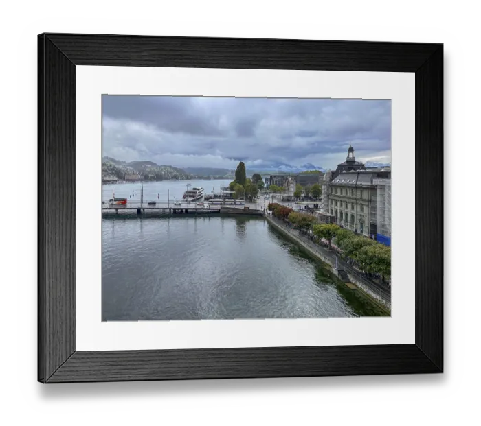 Framed Print : View of waterfront with boats and mountains in the background under cloudy sky