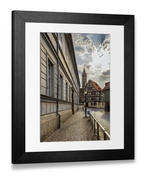 Framed Print : Historic city center with half-timbered houses and a church in the background under a partly cloudy sky