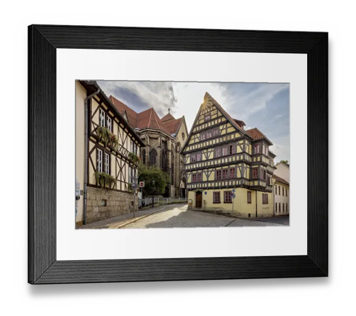 Framed Print : Sun-drenched street with half-timbered house and church Framed Print : Sun-drenched street with half-timbered house and church