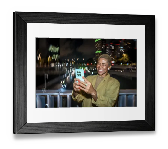 Framed Print : Smiling woman with short blond hair takes a nighttime smartphone selfie in an urban setting Framed Print : Smiling woman with short blond hair takes a nighttime smartphone selfie in an urban setting