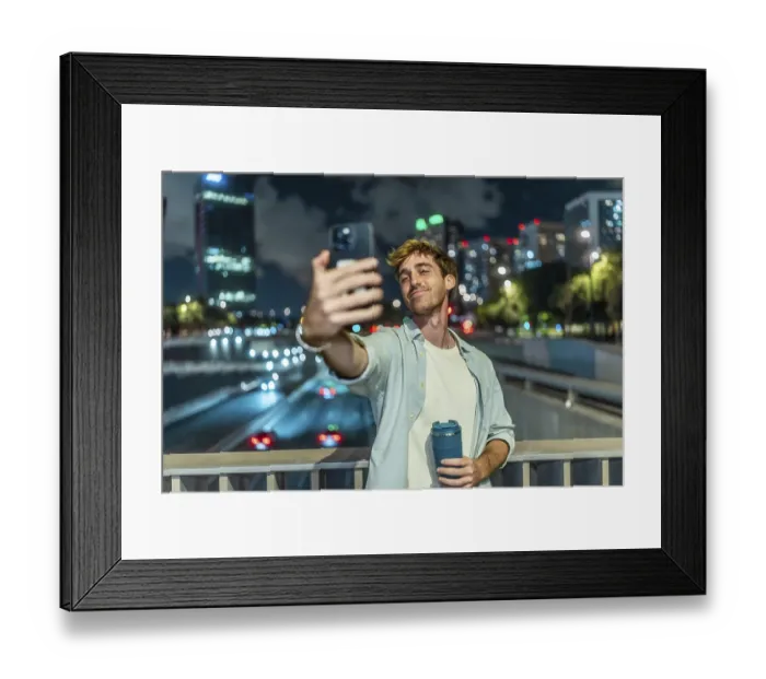 Framed Print : Young man smiling and taking a selfie with a smartphone Framed Print : Young man smiling and taking a selfie with a smartphone