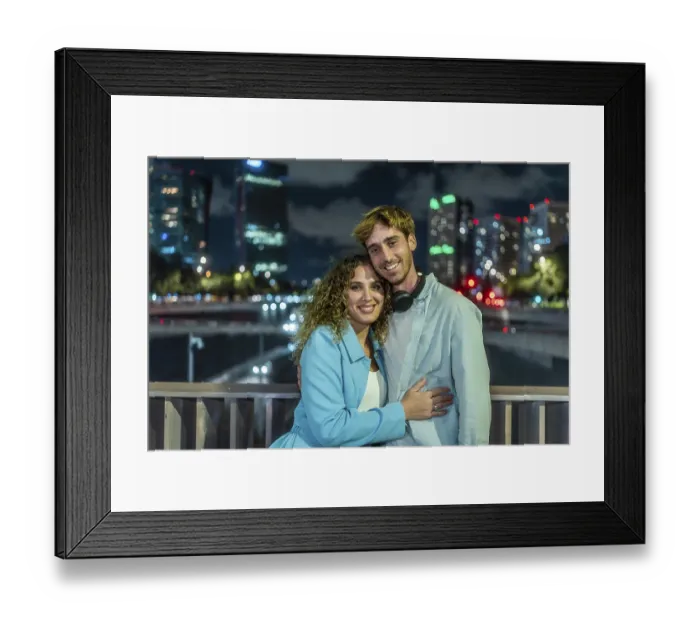Framed Print : Young couple embracing and smiling at the camera outdoors on a bridge