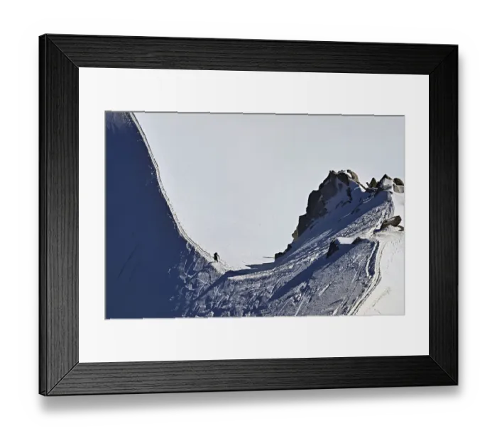 Framed Print : A mountaineer climbs over a snow-covered mountain ridge Framed Print : A mountaineer climbs over a snow-covered mountain ridge