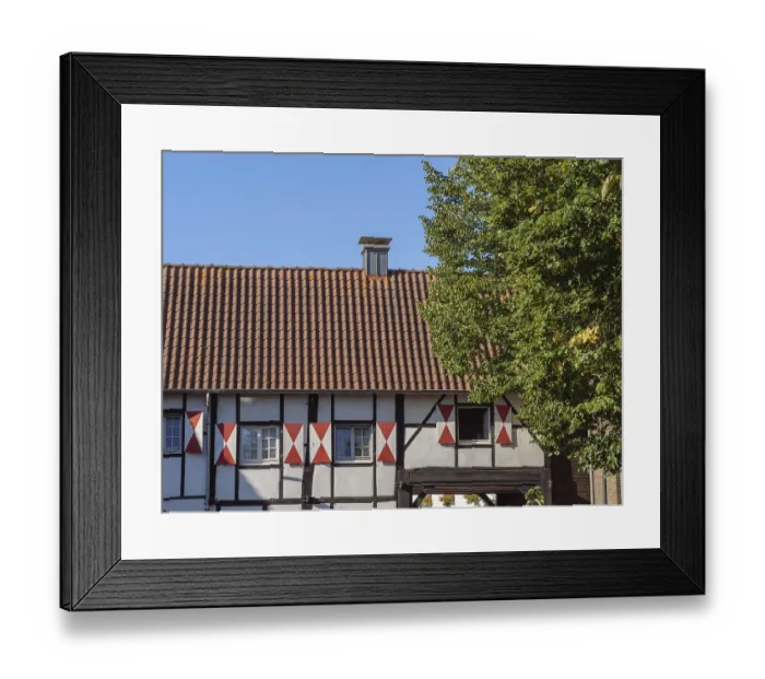 Framed Print : A rustic half-timbered house with red roof and trees in the background Framed Print : A rustic half-timbered house with red roof and trees in the background