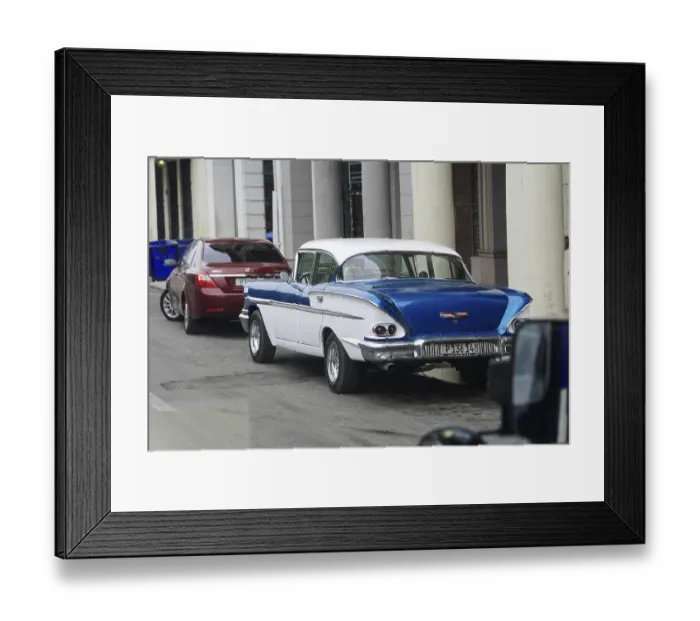 Framed Print : Blue and white classic car parked next to modern cars in the city