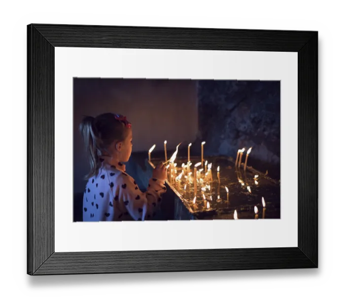Framed Print : Cute little caucasian girl lightening the memorial candles in the monastery