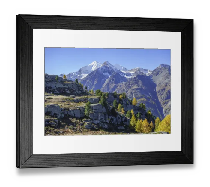 Framed Print : Snowy mountains with autumn trees and rocks under a blue sky