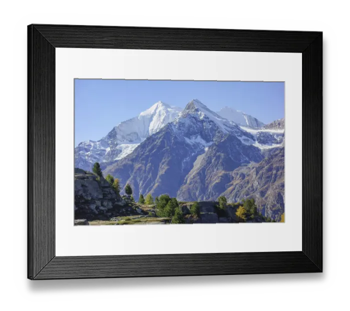 Framed Print : Snowy mountain peaks with rocks in the foreground under clear sky