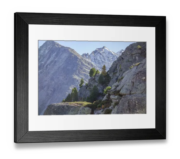 Framed Print : Rocks with trees against rugged mountain peaks under clear sky