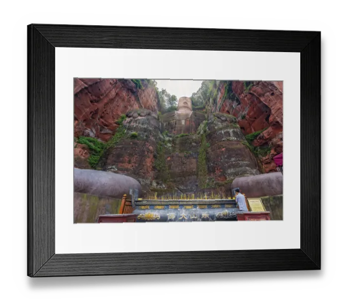 Framed Print : Leshan, China - July 2019 : Chinese male pilgrim lightening memorial candles at the bottom of The Giant Leshan Buddha