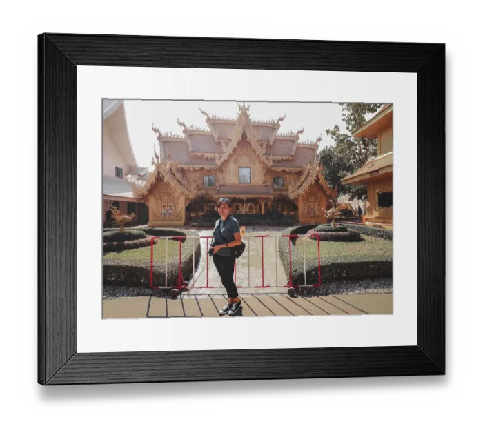 Framed Print : A woman posing in front of an ornate traditional thai temple with landscaped garden in Wat Rong Khun or White Temple