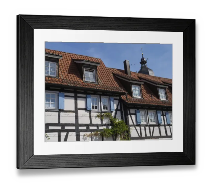Framed Print : A traditional half-timbered house with a red tile roof under a clear blue sky
