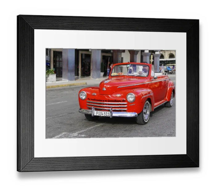 Framed Print : A bright red classic car drives as a taxi through city streets