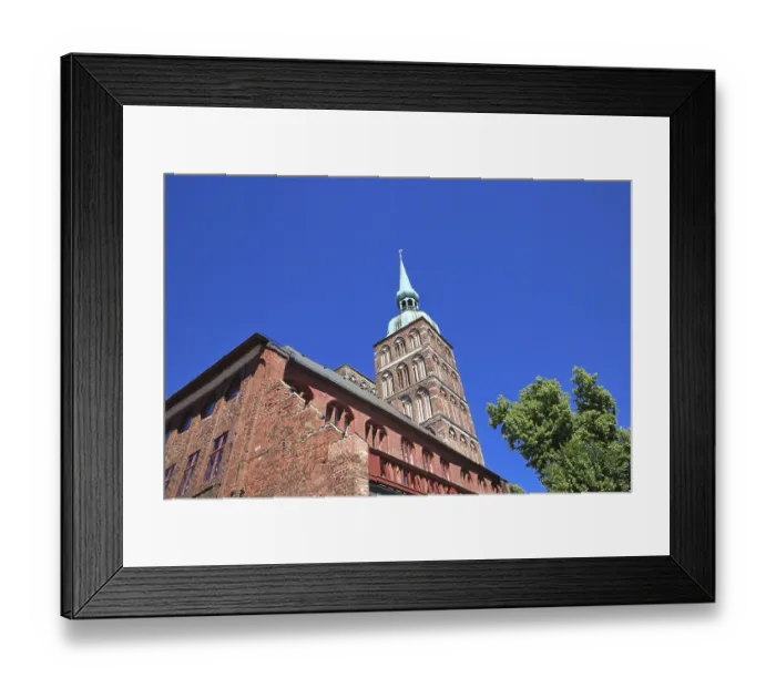 Framed Print : Gothic brick church tower against a clear blue sky next to green trees
