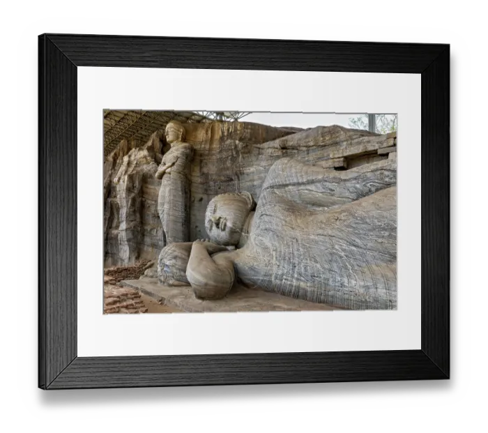 Framed Print : Close-up of the artistic detail of a large reclining Buddha statue next to a standing figure carved out of rocks