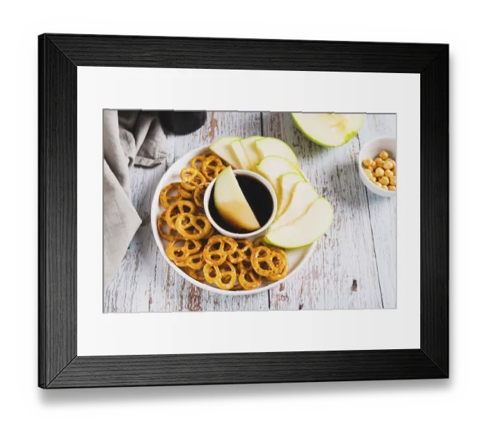 Framed Print : Crispy green apples and pretzels with miso caramel sauce on a plate on a table