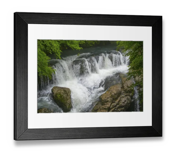 Framed Print : Small waterfall over rocks in a river surrounded by green trees